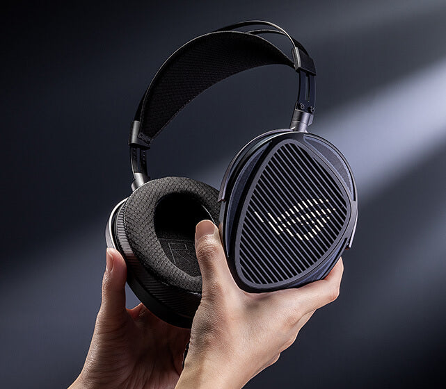 Hands holding the ROG Kithara headset, showing the open-back earcup design and ROG grille aesthetics