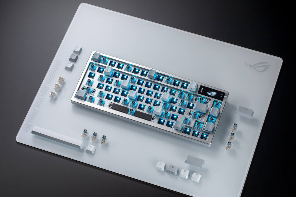 ROG Azoth Moonlight White with most key switches removed, alongside switches and keycaps placed at the side. ROG Moonstone Ace L is positioned beneath the keyboard.