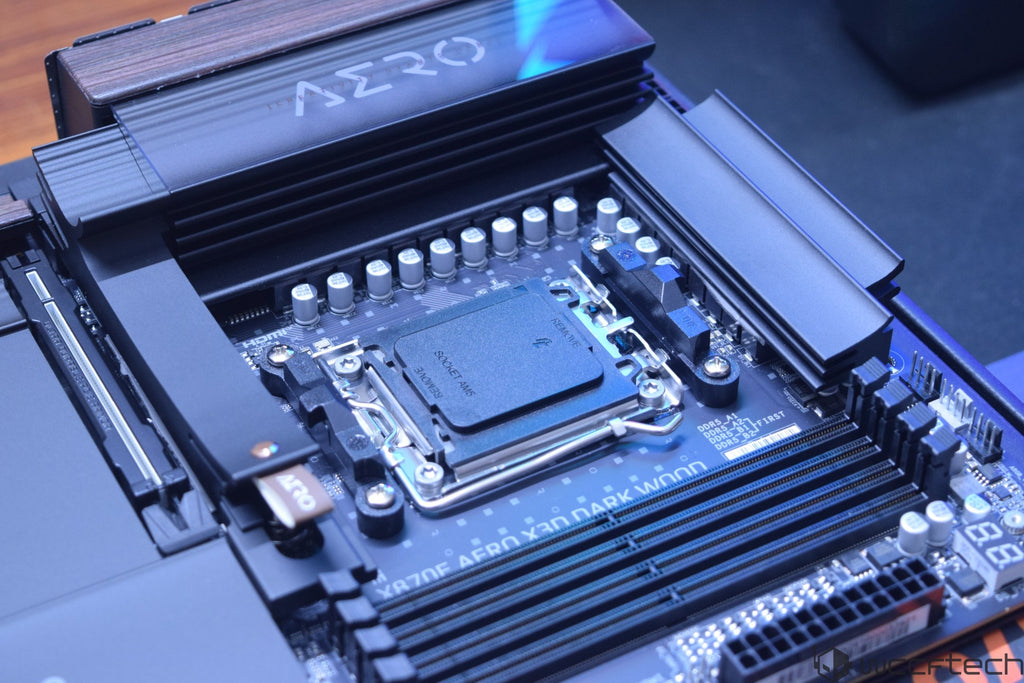 A GIGABYTE X670E AERO X3D DARK WOOD motherboard with visible DIMM slots and a socket labeled 