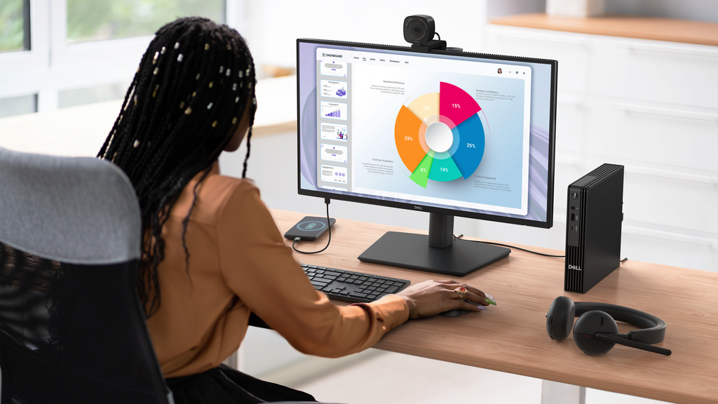 A person working at a desk with a Dell Pro 22 Plus and accessories like a wireless mouse, keyboard, headphones, and more.