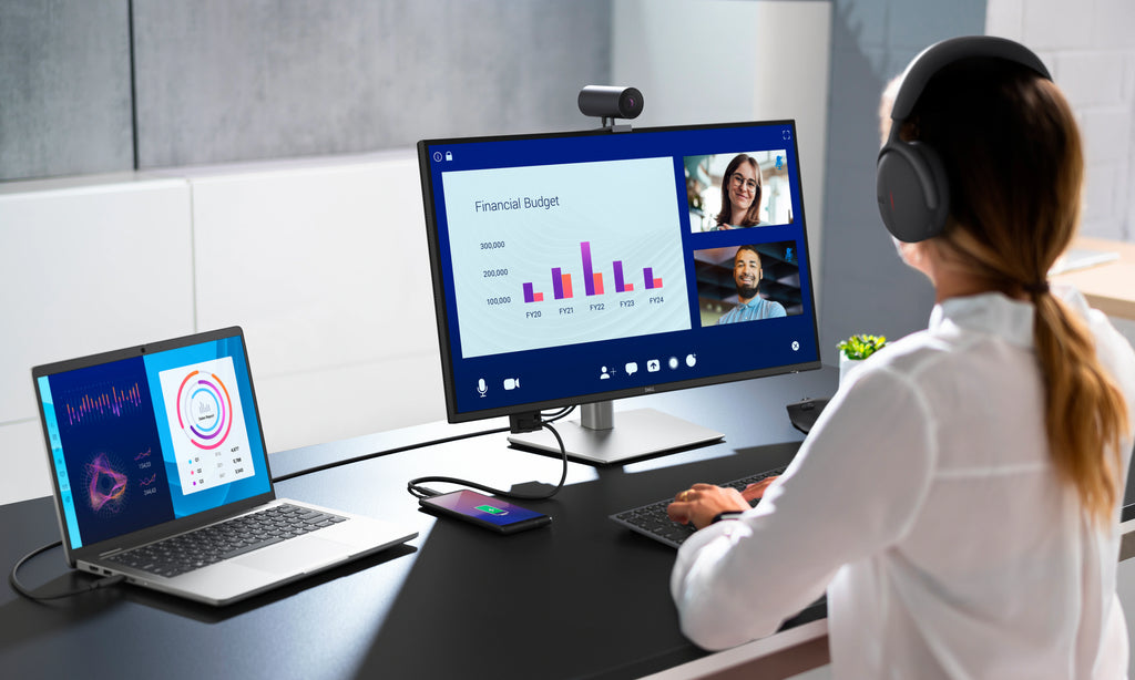  Businesswoman working on a Dell Pro 27 Plus 4K USB-C Hub Monitor, connected to a laptop, while wearing a headset.