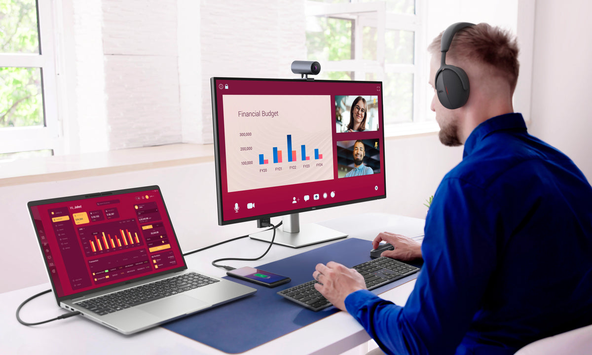 Businessman working on a Dell Pro 32 Plus 4K USB-C Hub Monitor, connected to a laptop, while wearing a headset.
