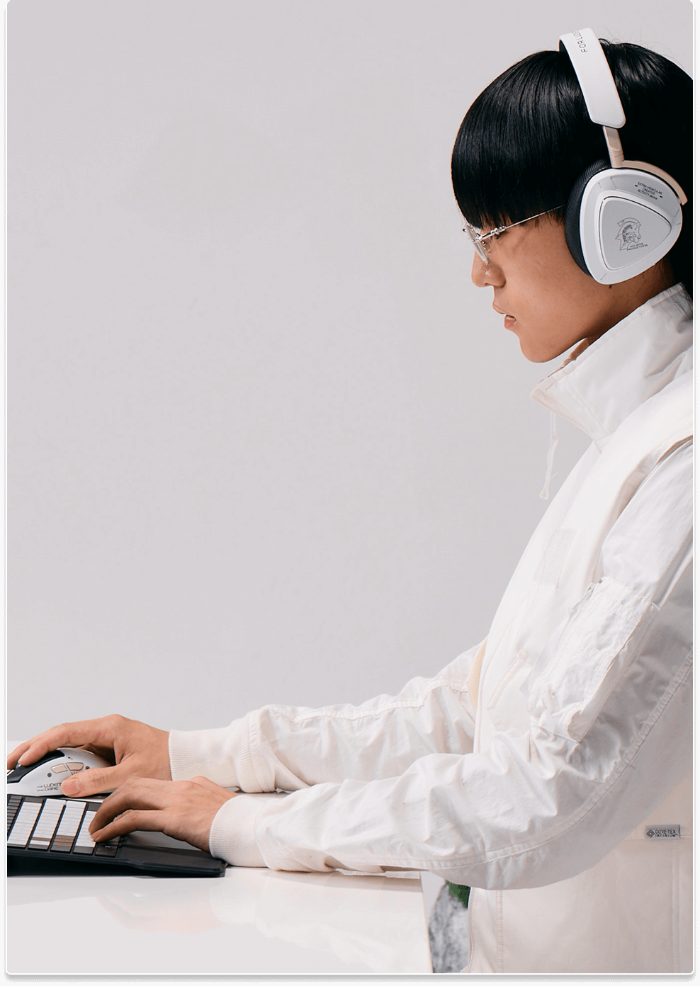 A person with the ROG Delta II-KJP headset on his head typing on the ROG Flow Z13-KJP