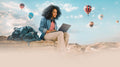 A young traveler seated outdoors on a rock, using a laptop with the RT-AX50 Go by side, against a backdrop of numerous hot air balloons dotting the blue sky.