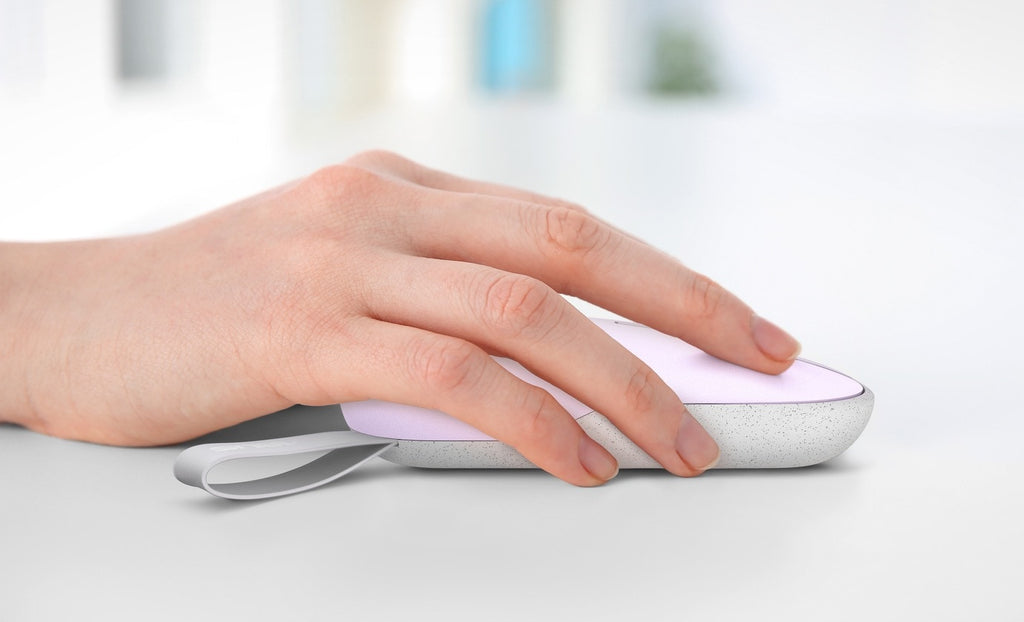 A close-up view of a woman’s hand clicking on an ASUS Marshmallow Mouse MD100 with a Lilac Purple finish.