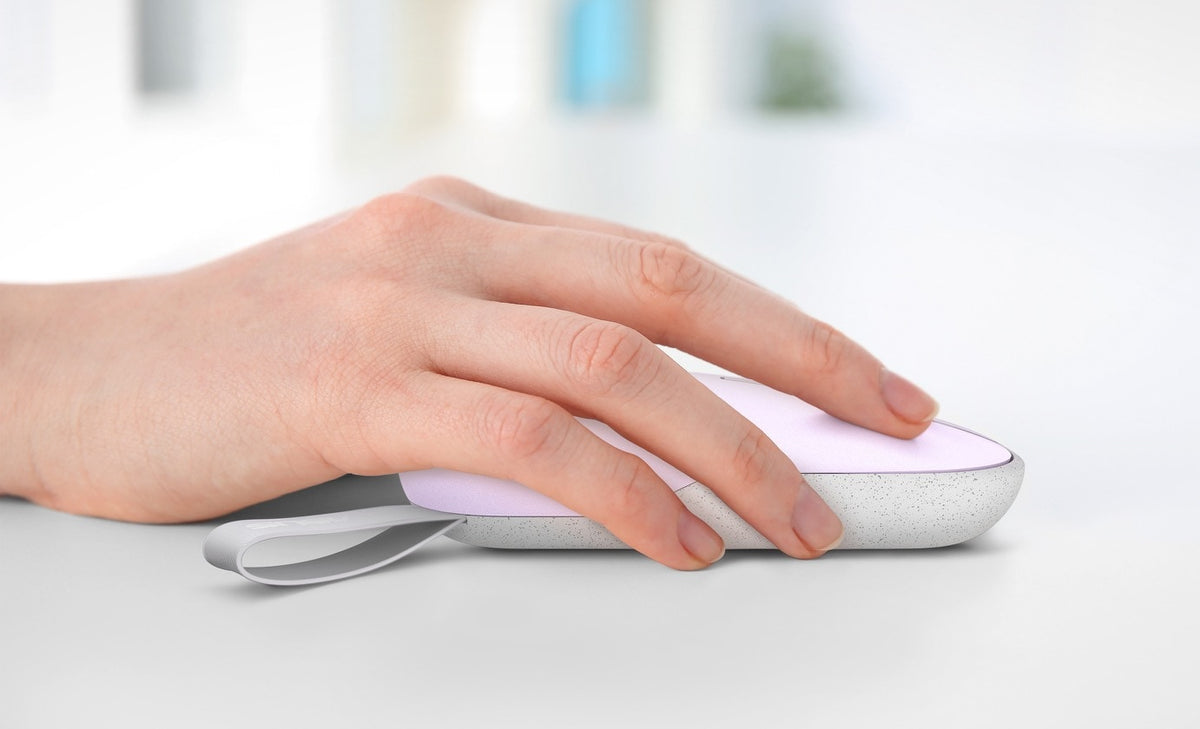 A close-up view of a woman’s hand clicking on an ASUS Marshmallow Mouse MD100 with a Lilac Purple finish.