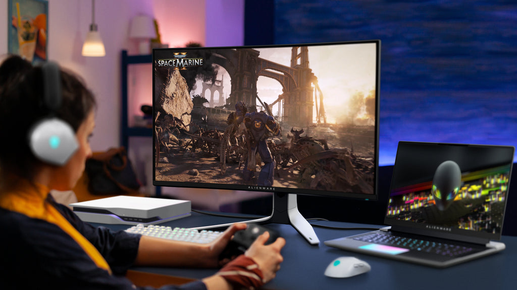 Woman playing Space Marine using Alienware products on a table in front of her.