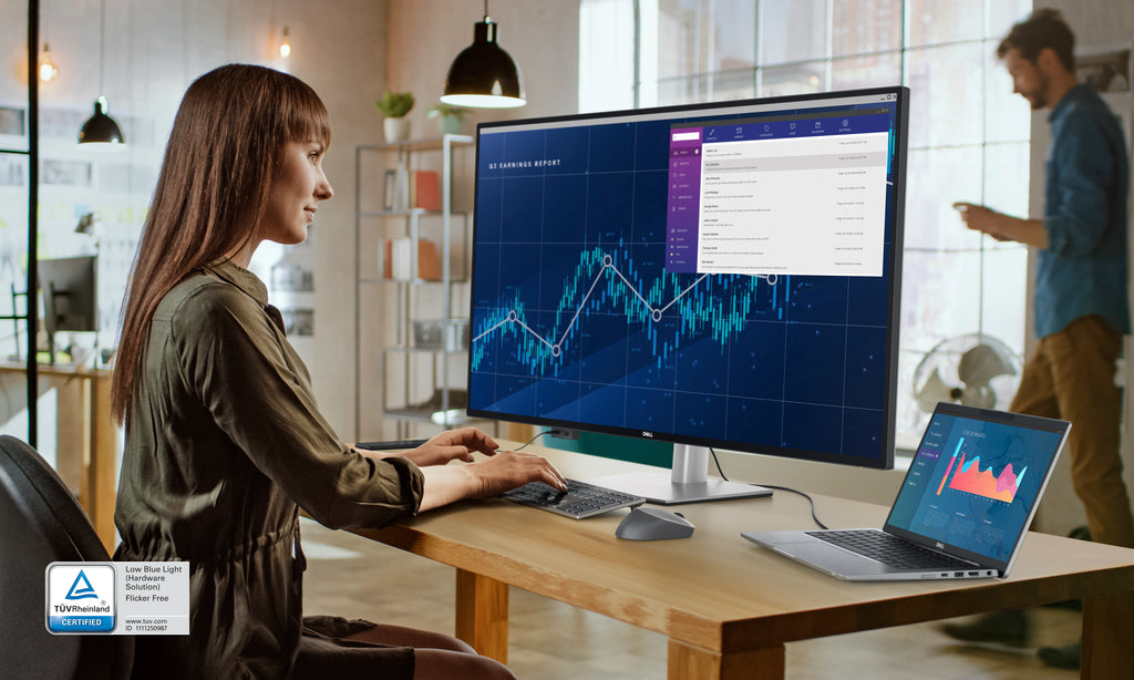 Woman sitting on an office chair typing on a keyboard and looking to a Dell UltraSharp U4323QE monitor.