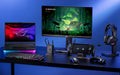 An ROG 100W Gaming Charger Dock plugged into a power port in the center of a desk, connected via HDMI to a monitor, and USB-C to an ROG Xbox Ally X. The desk also has an ROG Strix SCAR 16 laptop, wireless keyboard, wireless mouse, and an ROG headset on display.